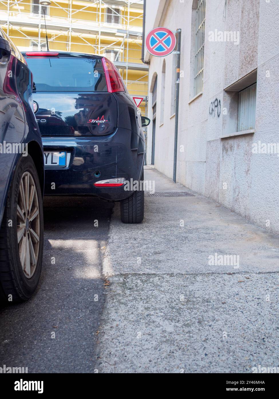Cremona, Italie 31 août 2024 Une voiture est stationnée illégalement bloquant un trottoir pour piétons à côté d'un panneau de signalisation de stationnement interdit Banque D'Images