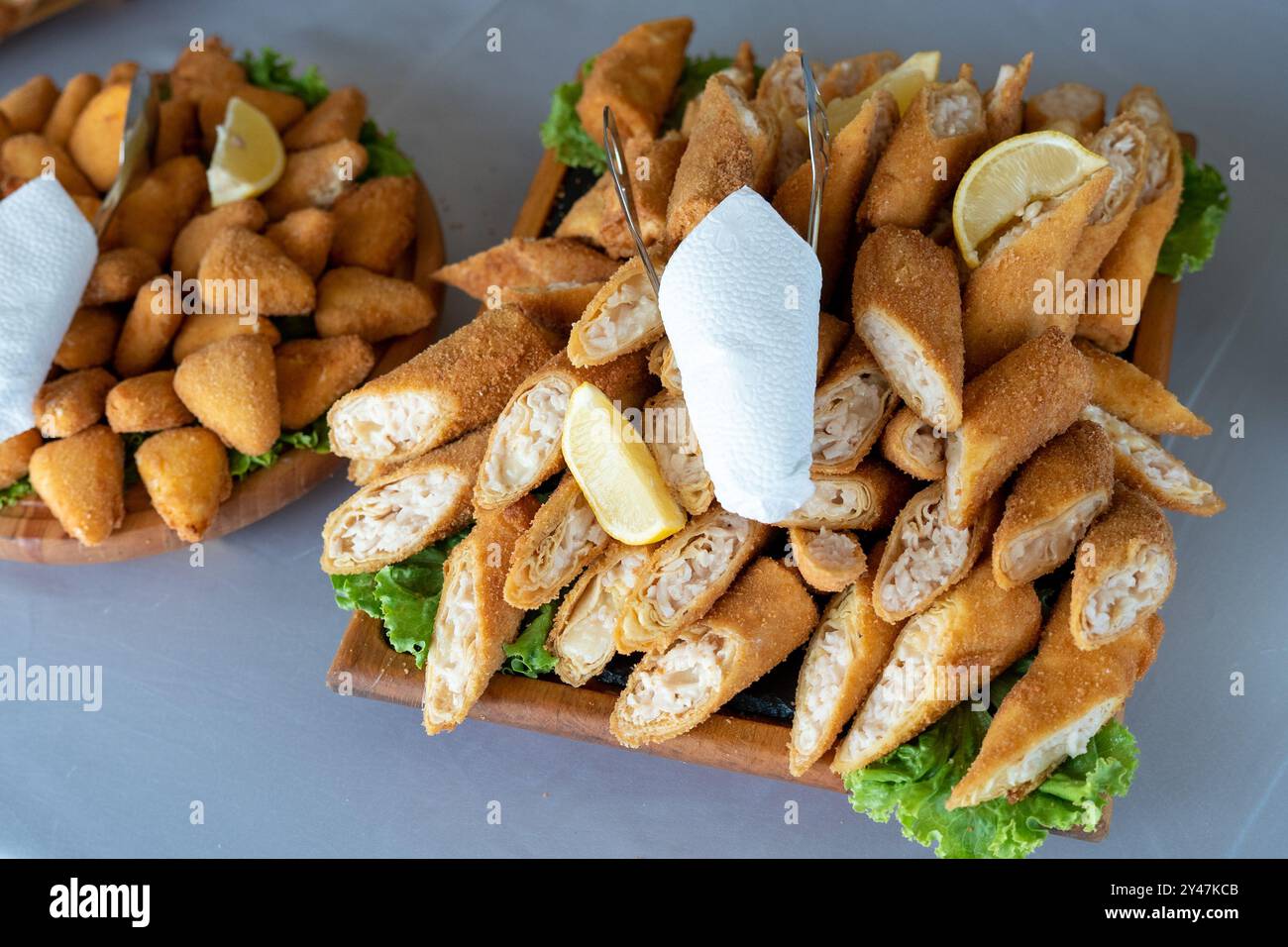 Tranches de chaussons ou boulettes avec farce au fromage salé et au jambon, avec des tranches de laitue et de citron comme décoration. Servi sur un drap de table blanc Banque D'Images