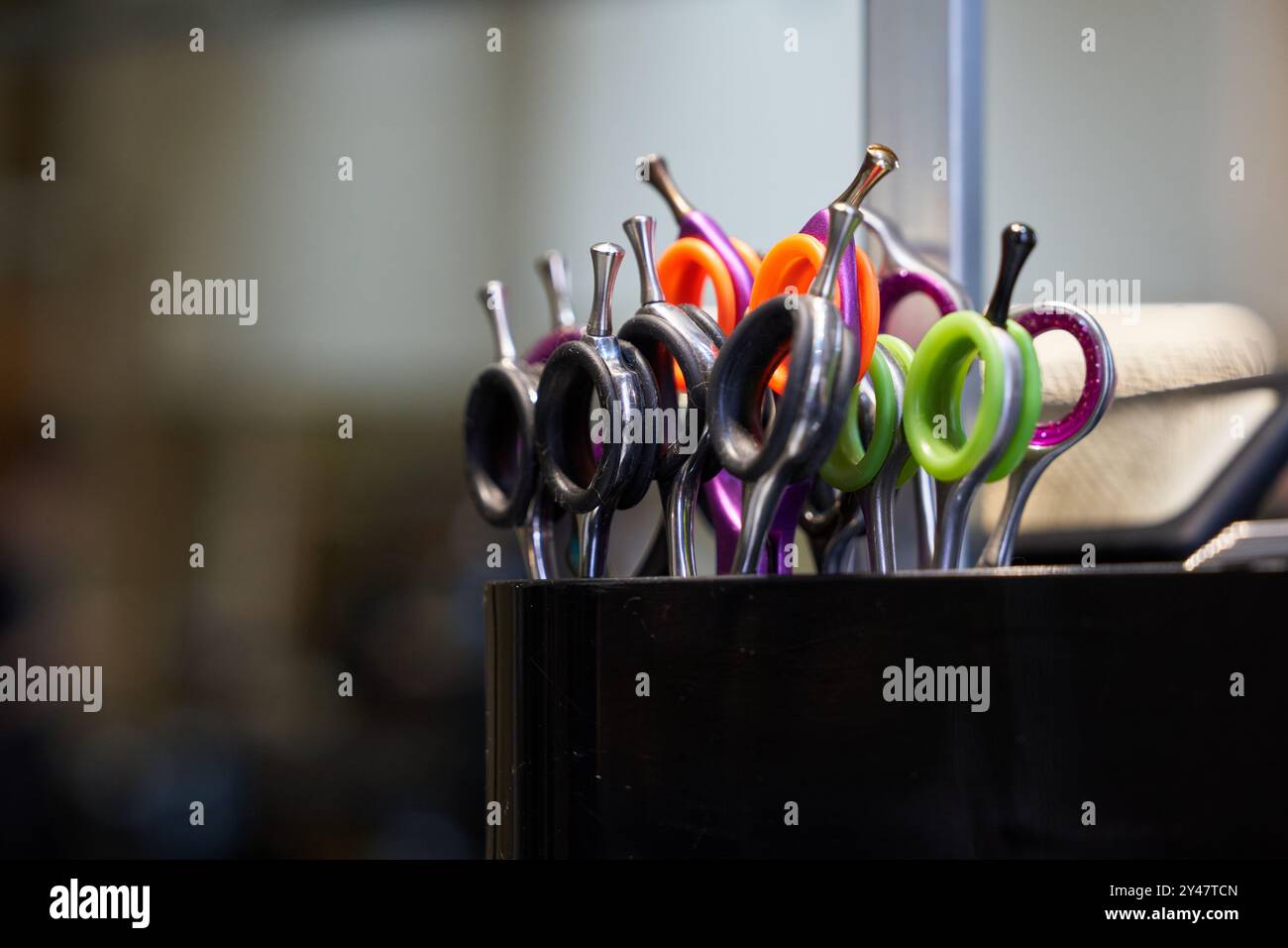 Ciseaux colorés de coupe de cheveux organisés dans un salon d'affichage à midi Banque D'Images