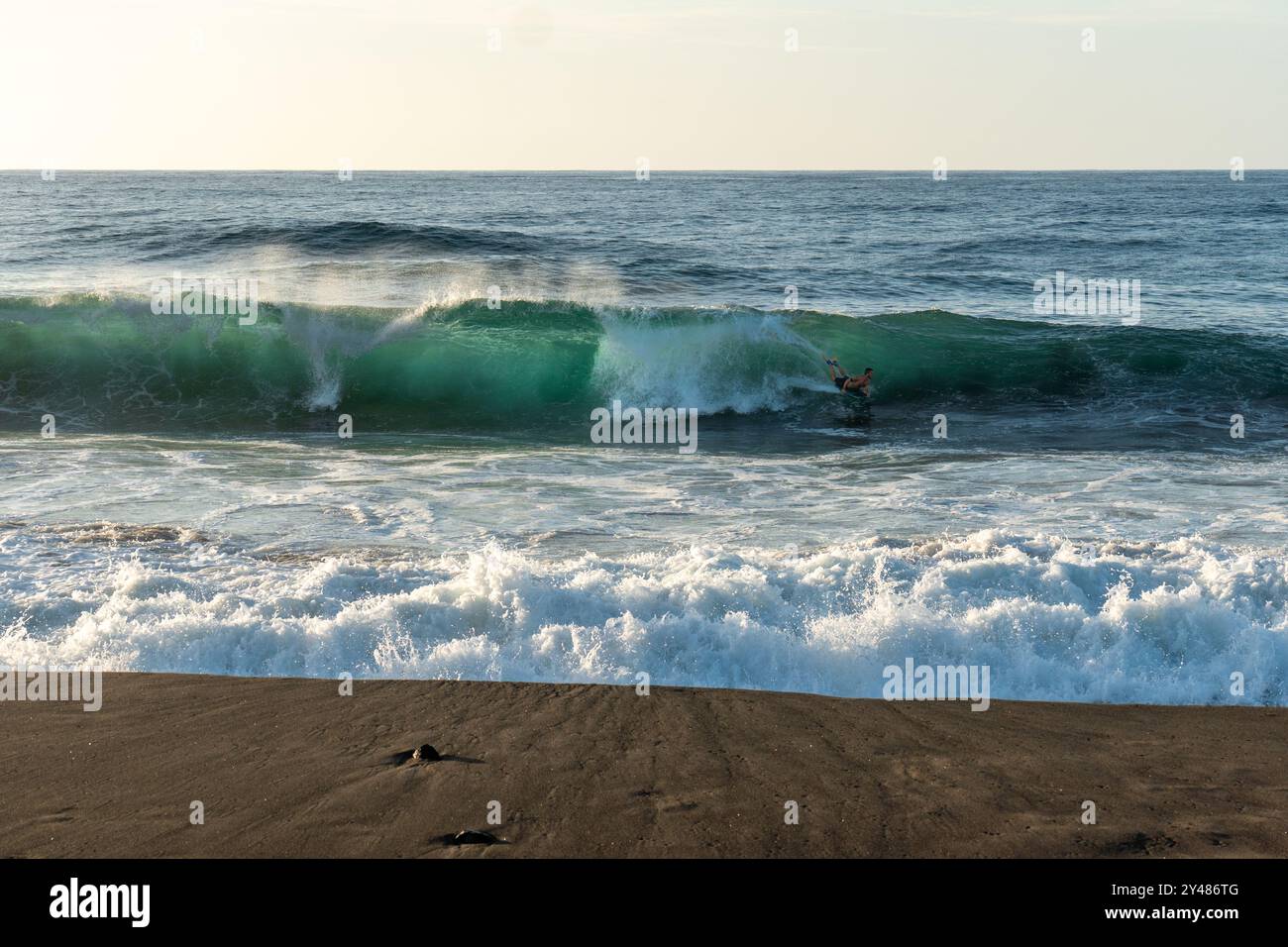 Surfeur chevauchant une vague massive et translucide sur un océan aigue-marine sur la plage de Santa Barbara Banque D'Images