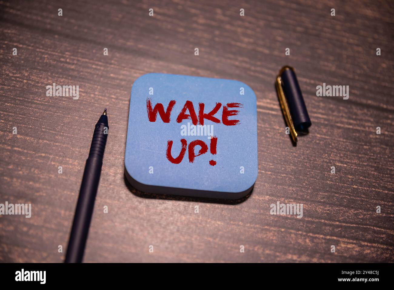 RÉVEILLEZ le texte sur un collant avec du café et un stylo sur fond de bois Banque D'Images