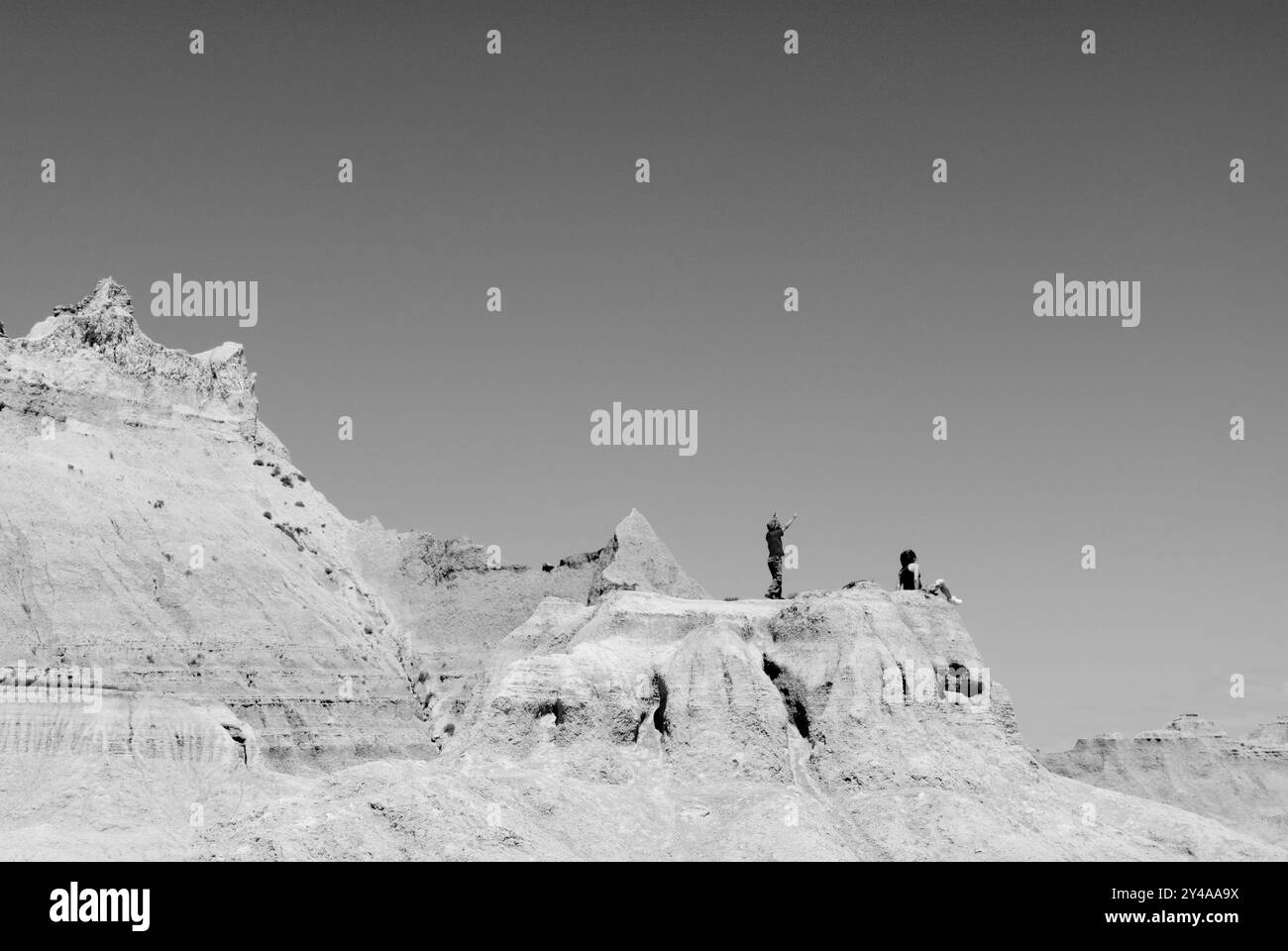 Deux personnes debout au sommet d'une colline au parc national des Badlands à l'intérieur, Dakota du Sud, États-Unis, surplombant les formations rocheuses étonnantes et expansive. Banque D'Images