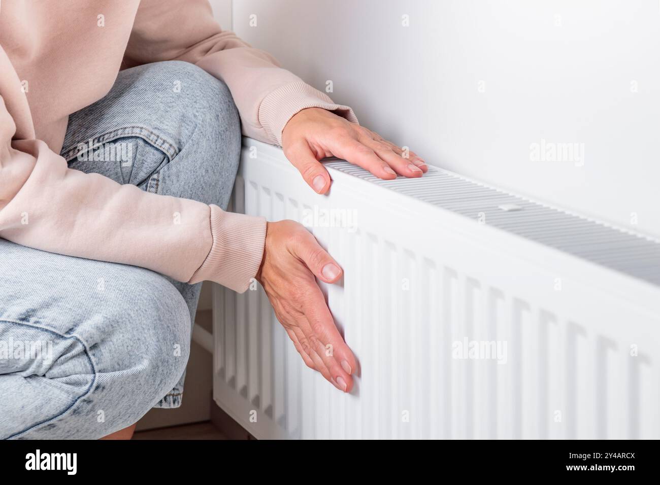 Une femme se réchauffant les mains sur un radiateur de chauffage, le concept de conservation de la chaleur et de l'énergie et l'importance de la gestion des ressources en mer froide Banque D'Images