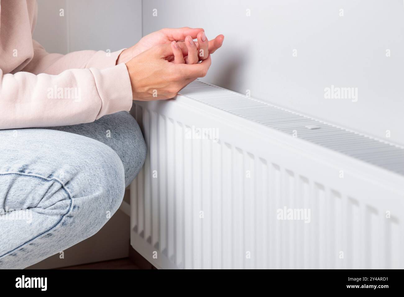 Une femme se réchauffant les mains sur un radiateur de chauffage, le concept de conservation de la chaleur et de l'énergie et l'importance de la gestion des ressources en mer froide Banque D'Images