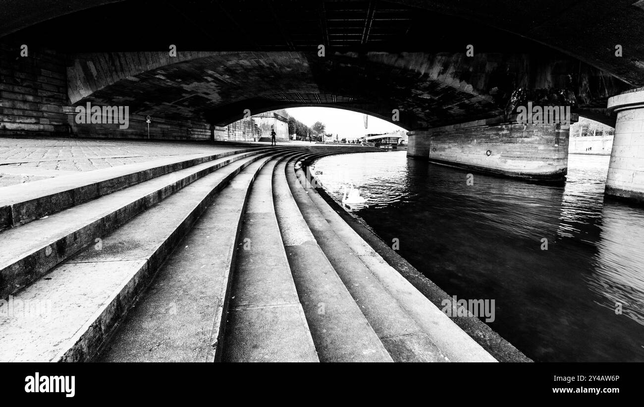 Les visiteurs se promènent le long des marches courbes de la Seine sous le pont d'Iéna à Paris, profitant de l'atmosphère tranquille et de la beauté architecturale des environs. Banque D'Images