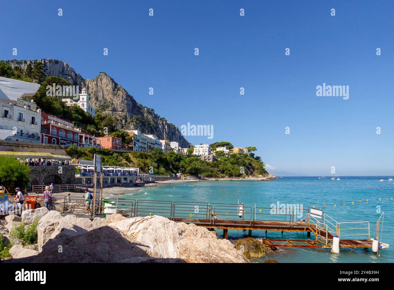 Vue panoramique sur la côte et les bâtiments colorés sur fond de falaises à Capri, Italie, avec un ciel bleu clair et des eaux turquoises Banque D'Images