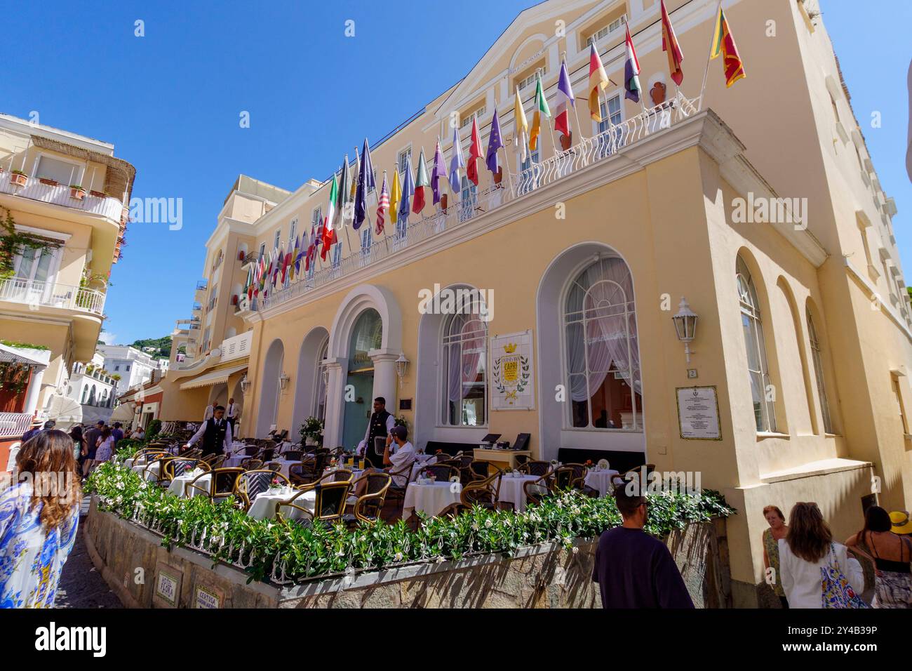 Café en plein air avec des gens sur une journée ensoleillée occupée, orné de drapeaux colorés de différents pays sur le Grand Hôtel Quisisana à Capri, Italie, Europe Banque D'Images