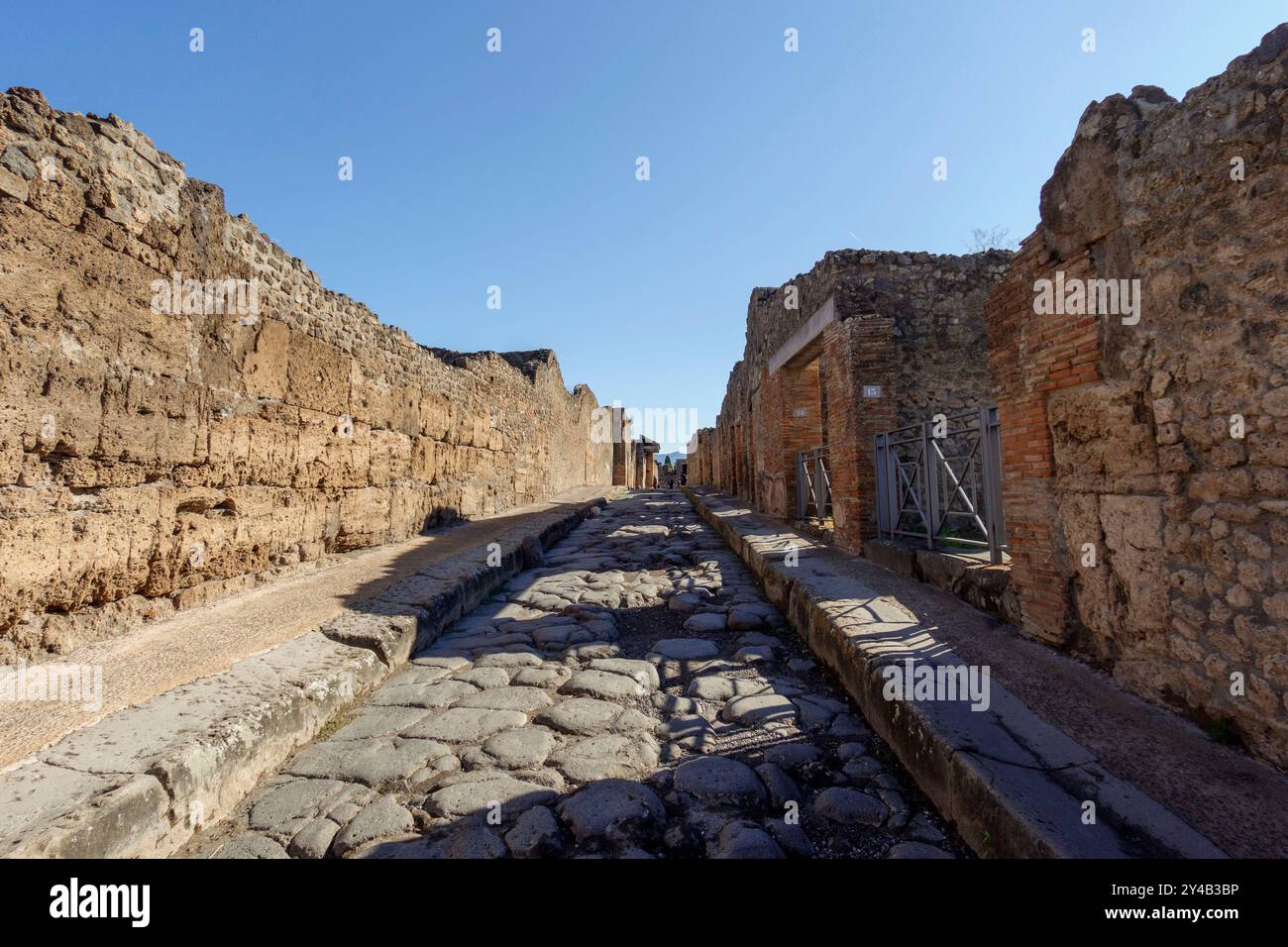 Ruines antiques à Pompéi sous un ciel bleu clair avec des structures historiques et des pavés visibles, Pompéi, Italie, Europe Banque D'Images