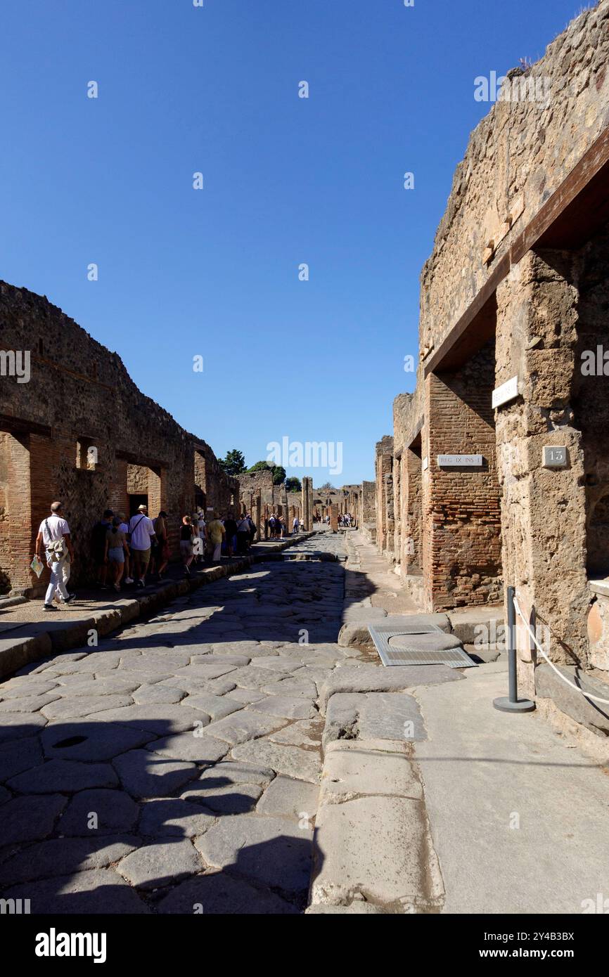 Les touristes explorent les ruines antiques de Pompéi, en Italie, avec un ciel bleu clair soulignant l'architecture historique Banque D'Images