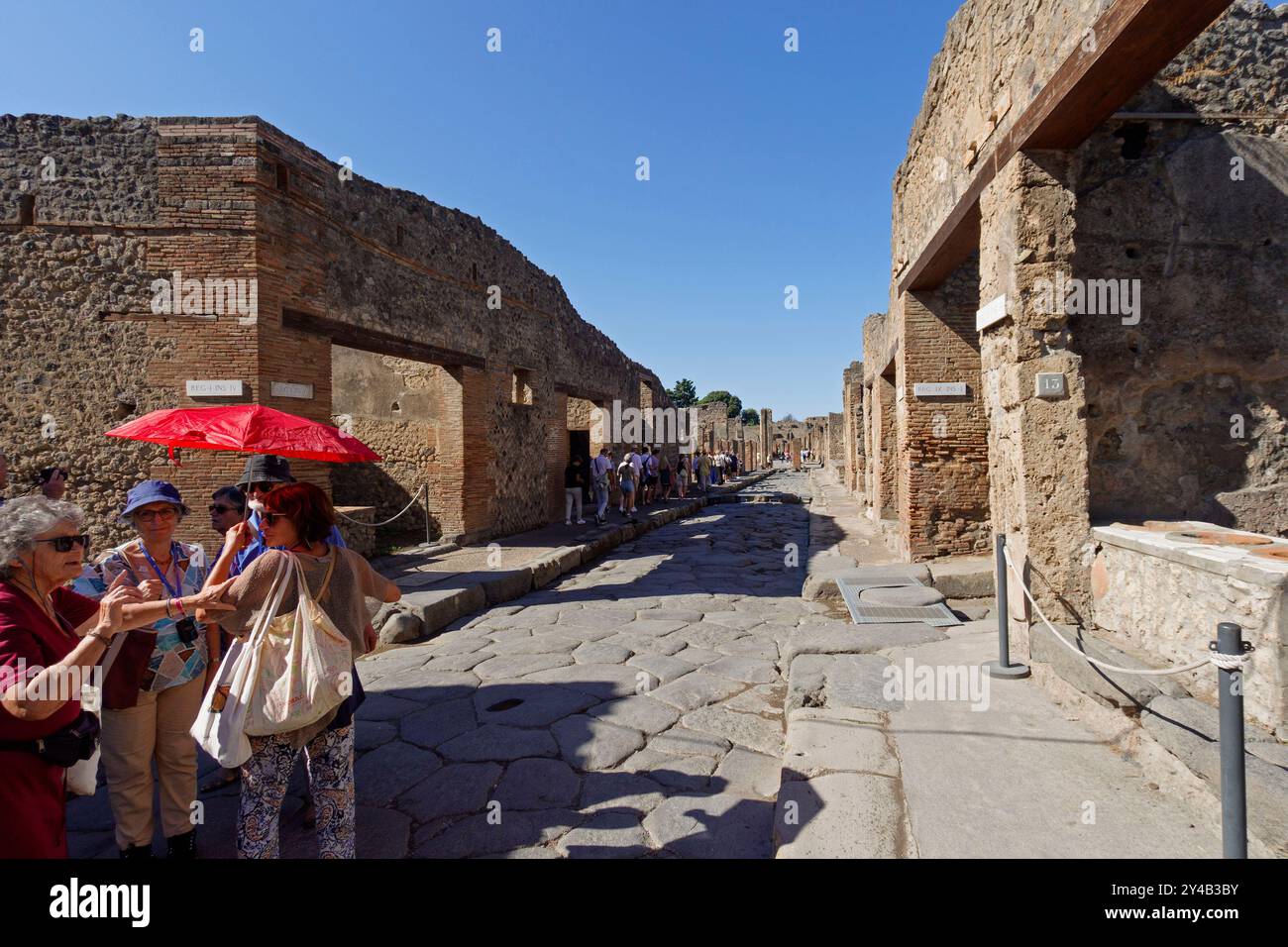 Les touristes explorent les ruines antiques de Pompéi, en Italie, avec un ciel bleu clair soulignant l'architecture historique Banque D'Images
