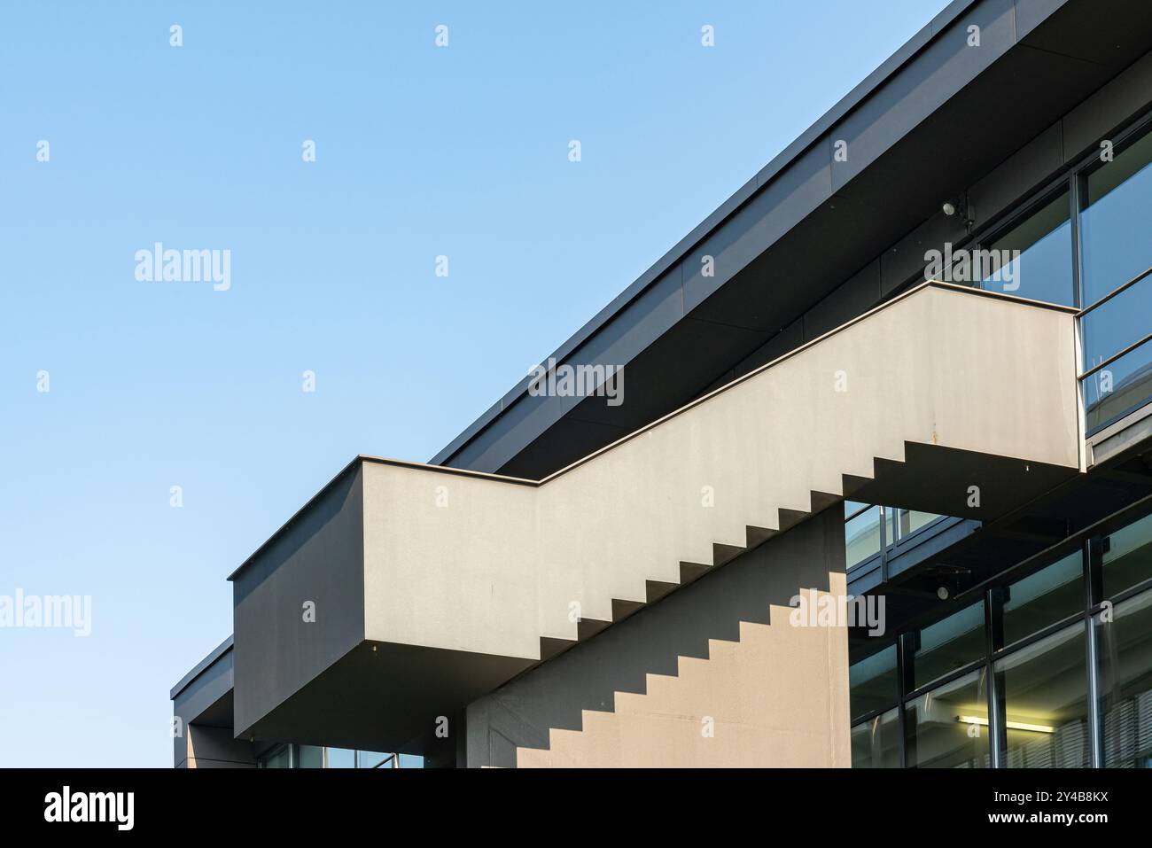 Un bâtiment frappant dispose d'un escalier en porte-à-faux unique s'étendant vers l'extérieur, encadré contre un ciel bleu clair, mettant en valeur l'architecture contemporaine Banque D'Images