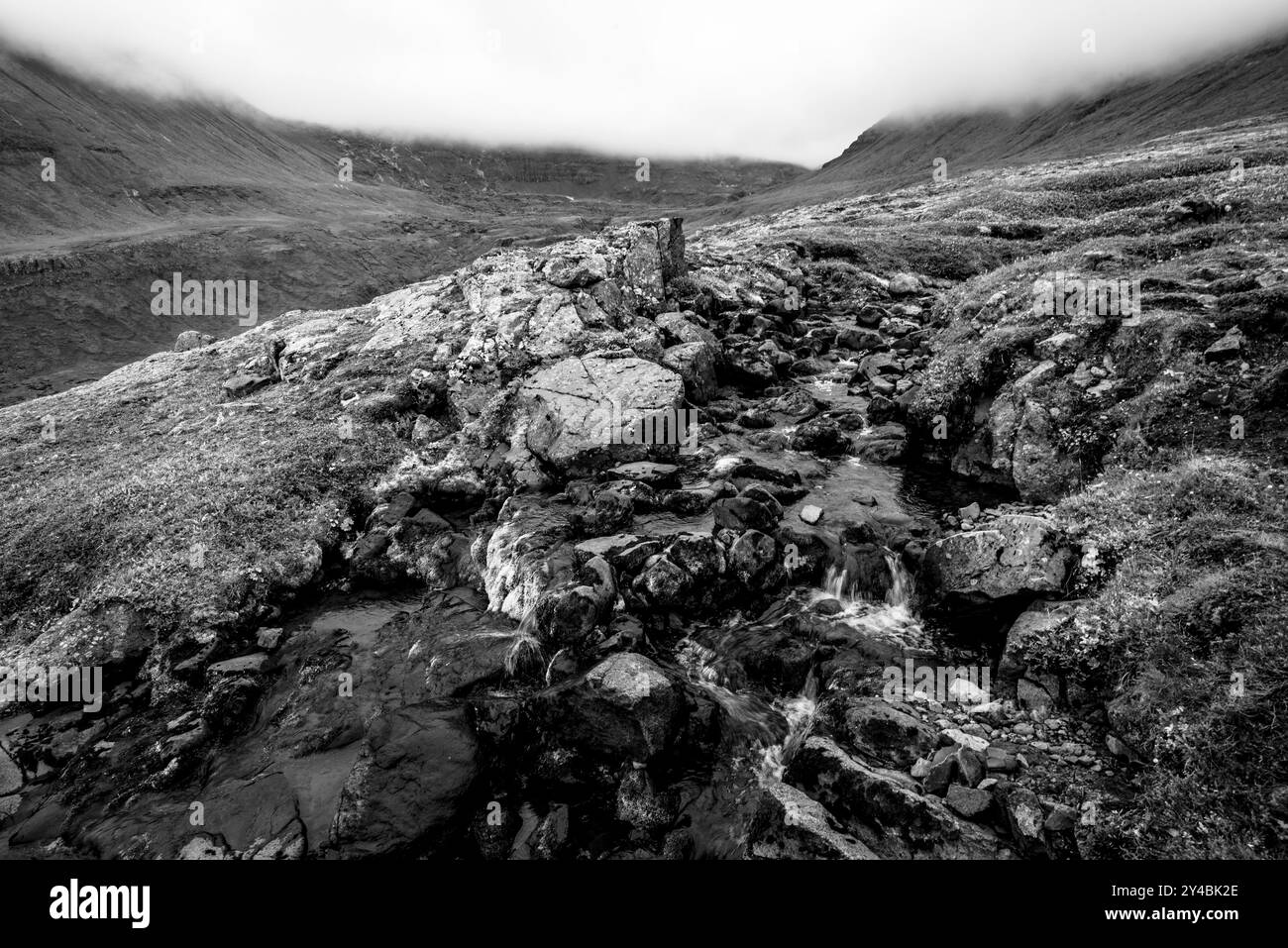 Ruisseau coule entre les roches volcaniques des pentes enneigées des montagnes autour de Borgarfiordur Eystri dans l'est de l'Islande Banque D'Images