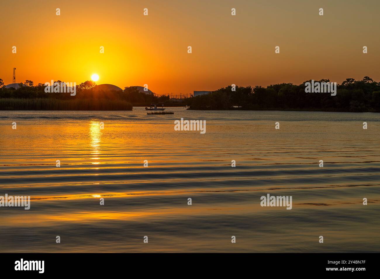 Réveillez-vous d'un bateau roule vers le rivage alors que le soleil se couche jetant une lueur sur les eaux Bayou. Banque D'Images