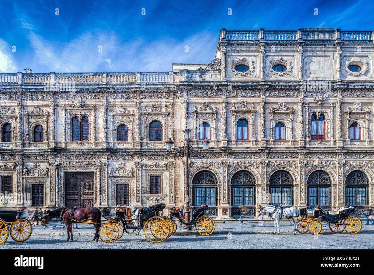 Des calèches vous attendent devant la façade plateresque ornée de l'hôtel de ville de Séville, qui présente l'architecture historique dans le quartier animé de Andalucía. Banque D'Images