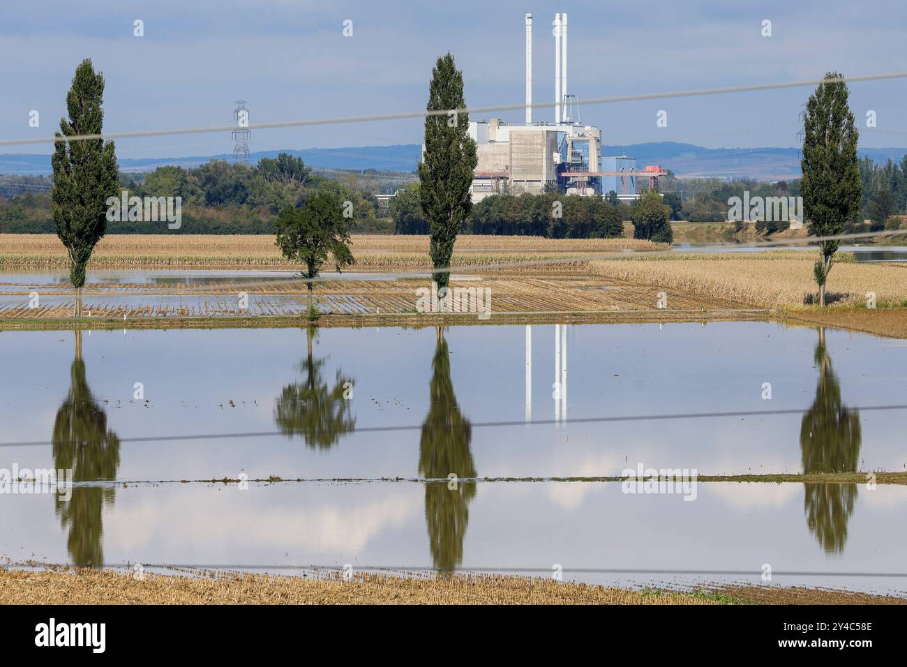 Atzenbrugg, Autriche. 17 septembre 2024. Les arbres se reflètent dans les eaux de crue sur les champs inondés ; la centrale à charbon-gaz de Dürnrohr à Zwentendorf sur le Danube peut être vue en arrière-plan. En Autriche, les eaux de crue reculent légèrement, mais la situation reste tendue et la menace de ruptures de barrages et de glissements de terrain persiste. Crédit : Christoph Reichwein/dpa/Alamy Live News Banque D'Images