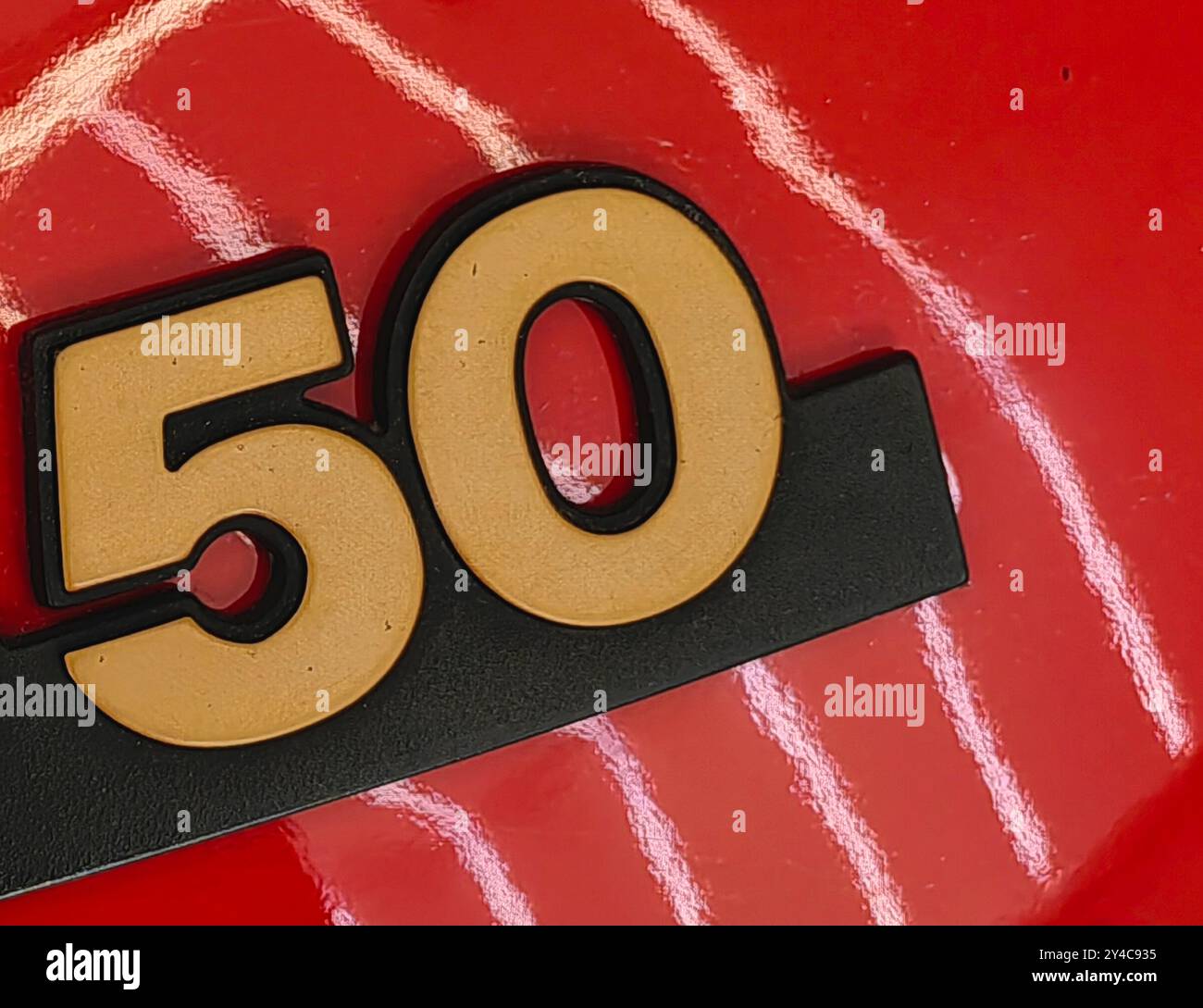 Numéro d'or 50 sur la surface rouge avec réflexion de lumière néon blanche. Banque D'Images