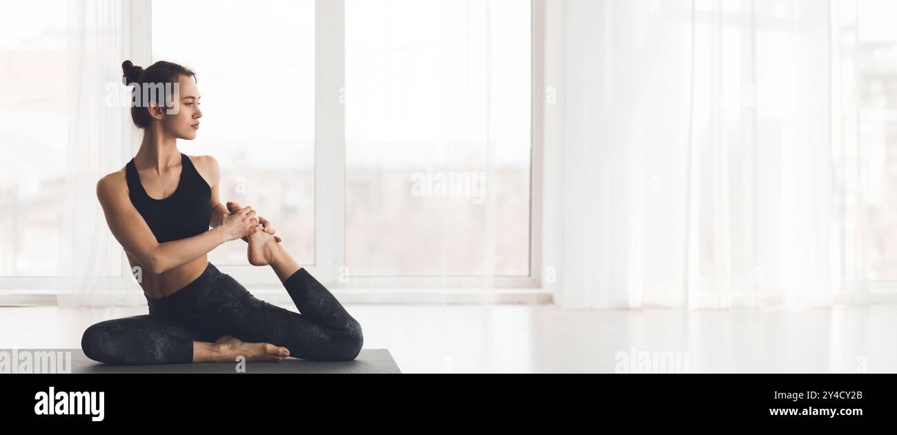 Femme pratiquant le yoga dans un studio intérieur lumineux pendant les heures du matin Banque D'Images