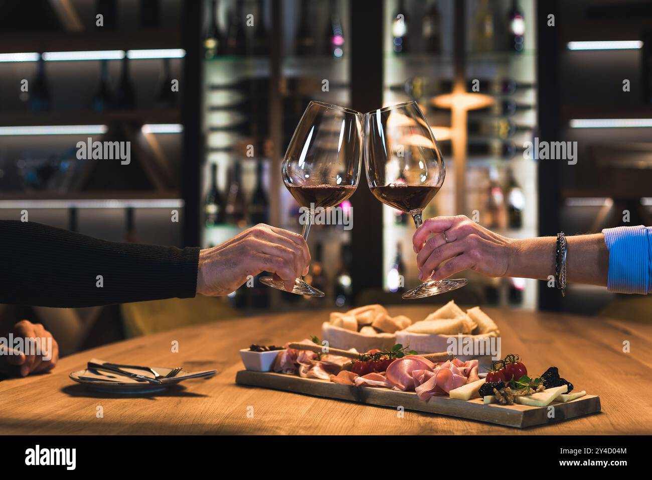 Couple souriant dînant dans une salle de cave à vin, dégustant du vin blanc fin et de la nourriture délicieuse Banque D'Images