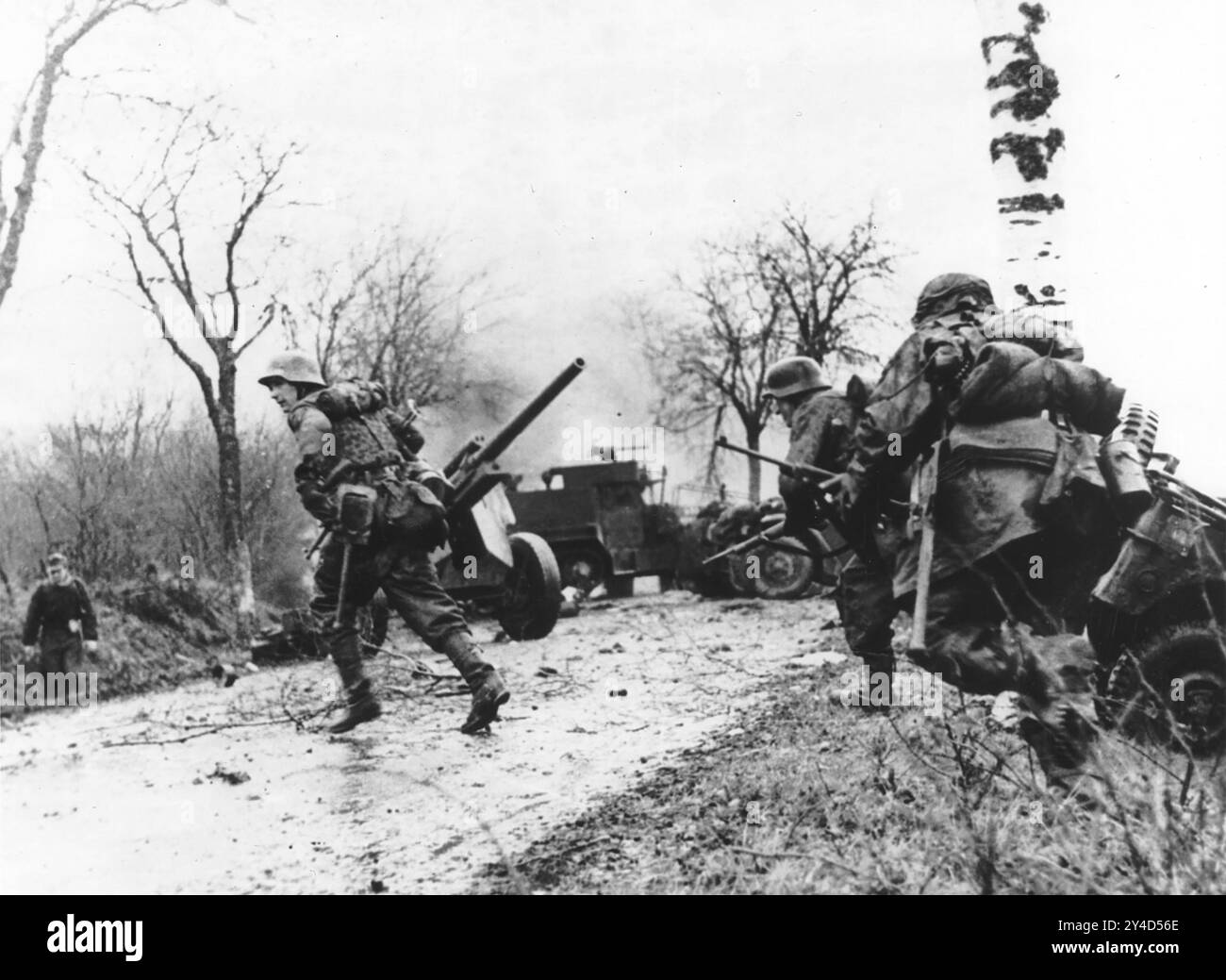 IL PARTICIPE À LA BATAILLE DE LA BULLE EN DÉCEMBRE 1944. Les soldats allemands du SS Kampfgruppe Hansen traversent une route dans des transports américains épaves passés. Banque D'Images