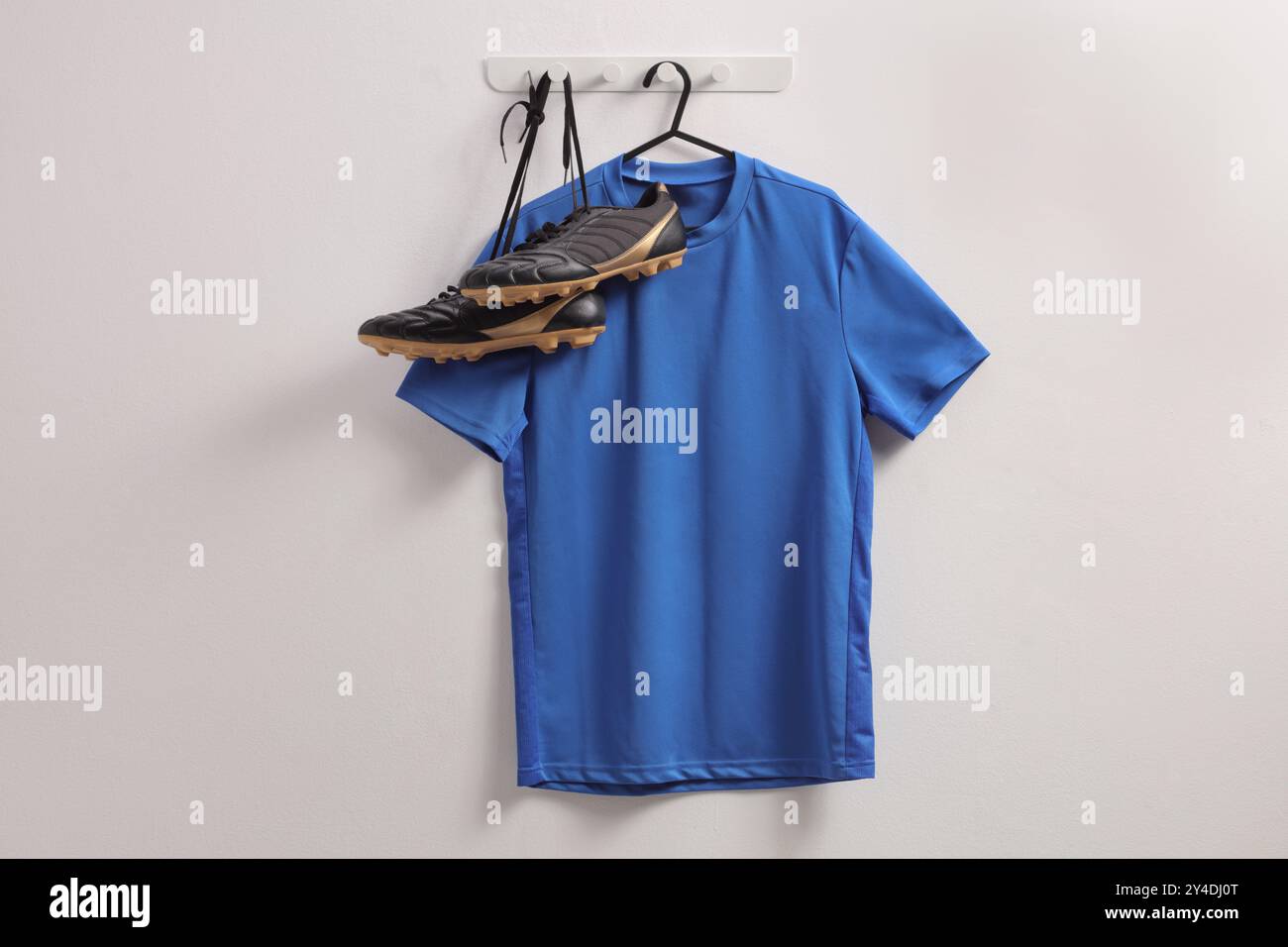 T-shirt de football bleu et crampons accrochés à un mur Banque D'Images
