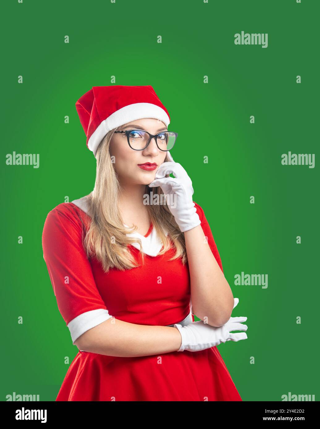 Jeune femme blonde avec des lunettes habillées en Père Noël à Noël regardant la caméra sérieusement sur un fond vert Banque D'Images