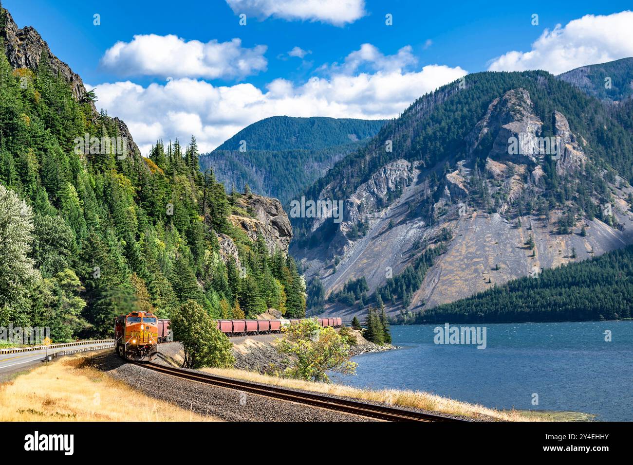 Vue paysage de la locomotive tire un train de wagons de marchandises sur un chemin de fer le long de la rivière Columbia dans la région pittoresque de Columbia gorge avec moun Banque D'Images