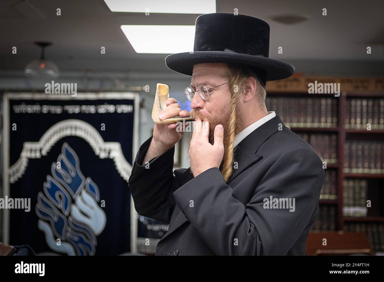 Un homme juif orthodoxe souffle un shofar lors des offices du matin comme c'est la coutume dans le mois précédant le nouvel an juif. Dans le comté de Rockland, NY. Banque D'Images