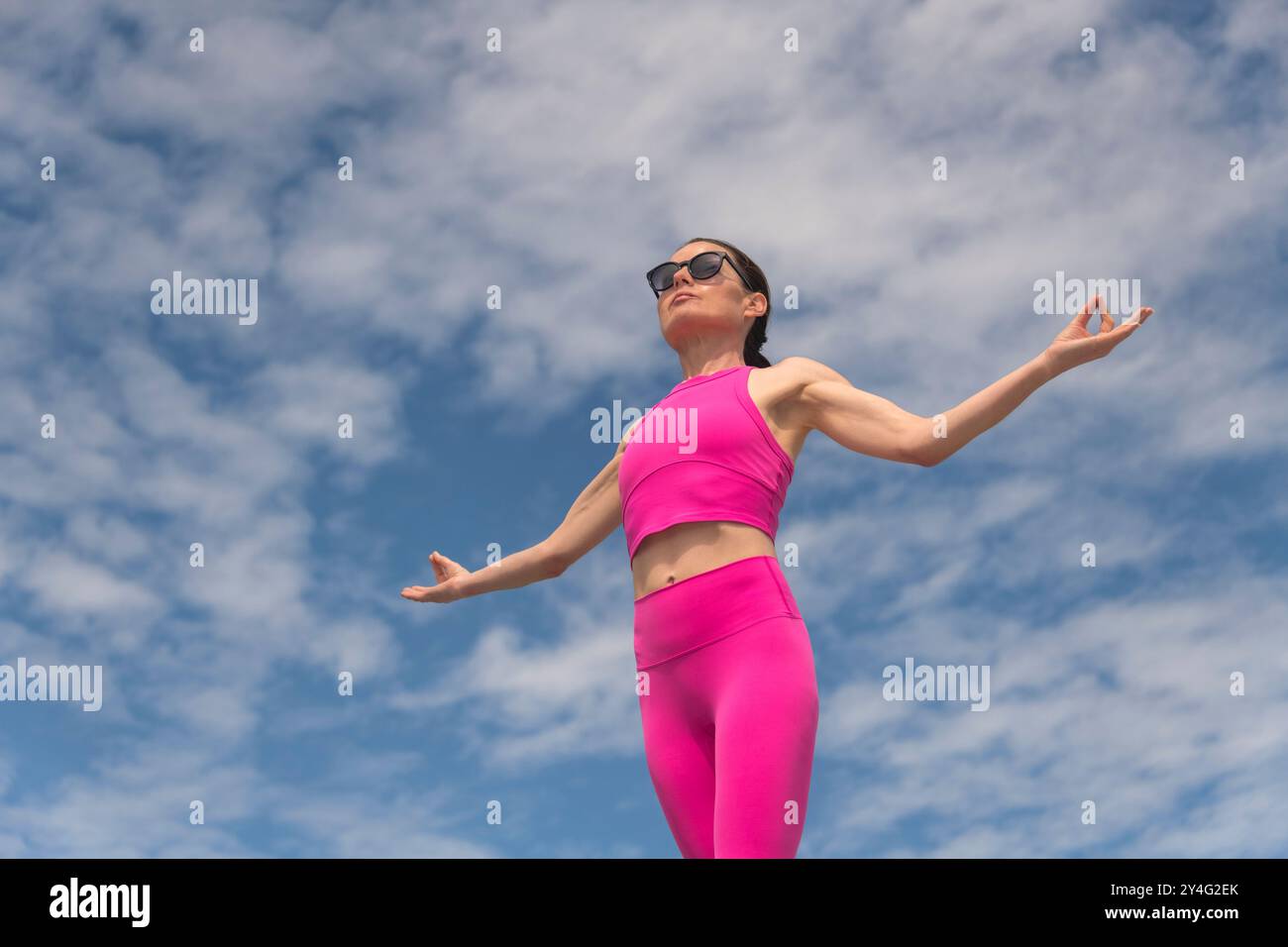 Femme debout méditant avec ses bras levés, exercice de respiration pour déstresser Banque D'Images Femme debout méditant avec ses bras levés, exercice de respiration pour déstresser Banque D'Images