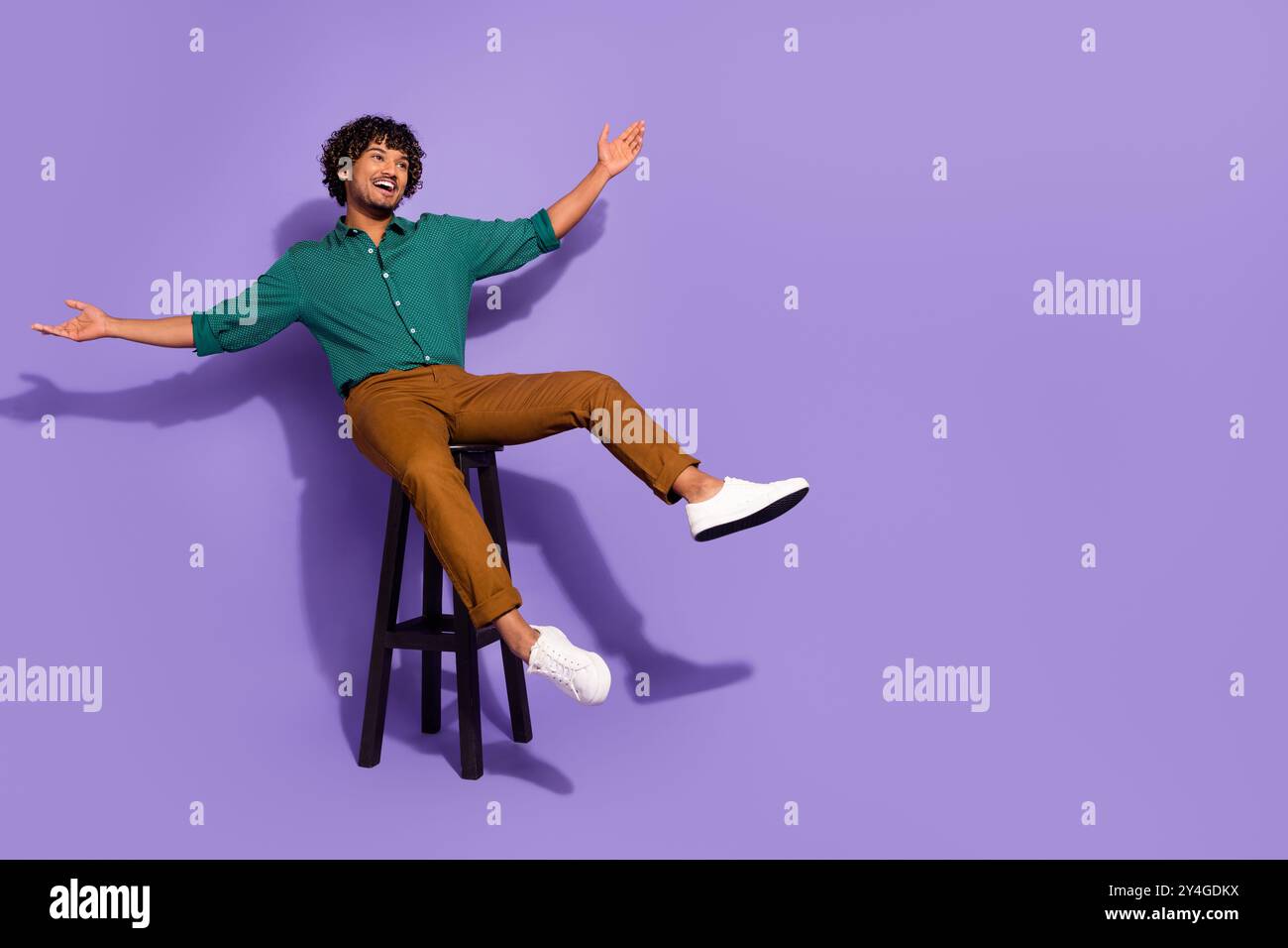 Photo pleine longueur du corps d'un beau gars hispanique dans le bar se refroidissant chaise assise détendue bras levés isolés sur fond de couleur violette Banque D'Images