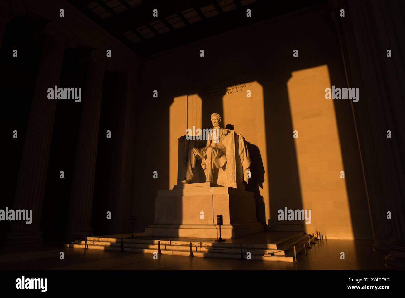 Lincoln Memorial Statue Sunlight Washington DC // WASHINGTON DC — la statue d'Abraham Lincoln à l'intérieur du Lincoln Memorial est illuminée par la lumière naturelle dorée du soleil juste après le lever du soleil. Cet effet lumineux, visible autour de l'équinoxe de printemps et d'automne, renforce la grandeur du monument lorsque le soleil brille à travers l'entrée est. Le Lincoln Memorial, situé sur le National Mall, est l'un des monuments les plus emblématiques des États-Unis. NB : la couleur et l'éclairage sont naturels. Banque D'Images