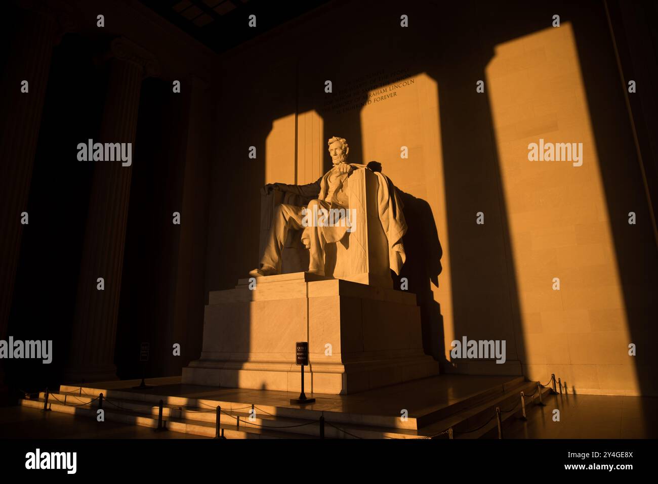 Lincoln Memorial Statue Sunlight Washington DC // WASHINGTON DC — la statue d'Abraham Lincoln à l'intérieur du Lincoln Memorial est illuminée par la lumière naturelle dorée du soleil juste après le lever du soleil. Cet effet lumineux, visible autour de l'équinoxe de printemps et d'automne, renforce la grandeur du monument lorsque le soleil brille à travers l'entrée est. Le Lincoln Memorial, situé sur le National Mall, est l'un des monuments les plus emblématiques des États-Unis. NB : la couleur et l'éclairage sont naturels. Banque D'Images