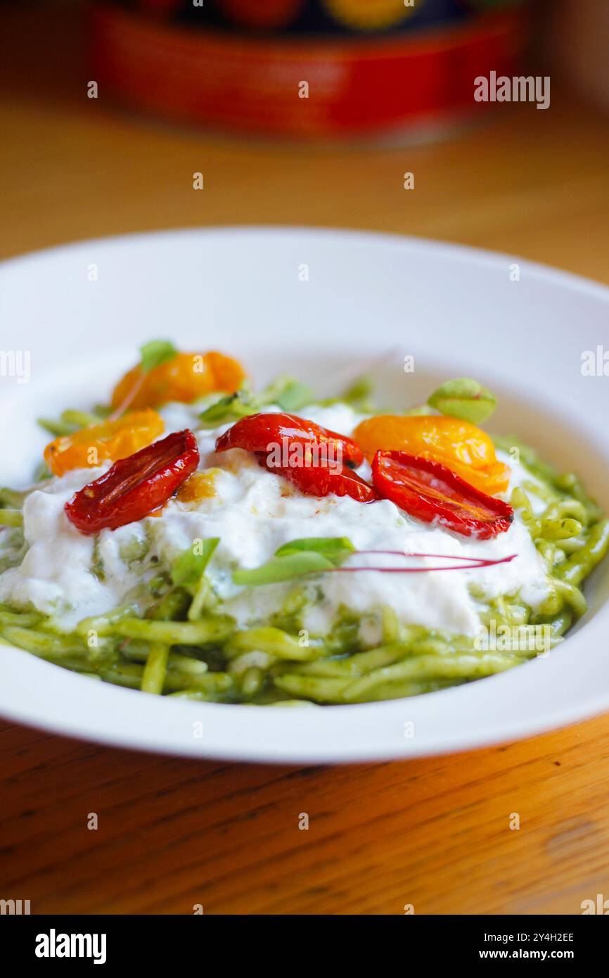 Gros plan de pâtes de la trofia italienne avec pesto, burrata et tomates cerises servies sur une assiette blanche. Cuisine italienne (Ligurie), focus sélectif Banque D'Images
