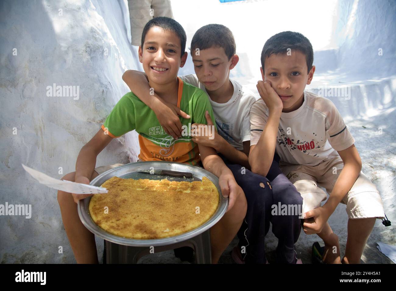 Chefchaouen, Maroc, le 3 juillet 2007, trois enfants sont heureux de présenter leurs gâteaux faits maison en vente à Chefchaouen, mettant en valeur l’entrepreneuriat local Banque D'Images