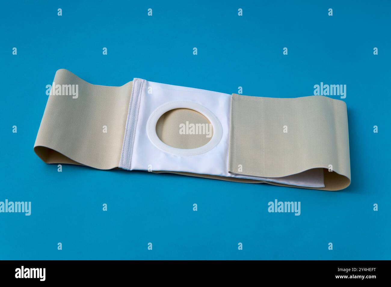 une ceinture abdominale dépliée, avec une ouverture de stomie pour les patients de colostomie, sur fond bleu Banque D'Images une ceinture abdominale dépliée, avec une ouverture de stomie pour les patients de colostomie, sur fond bleu Banque D'Images