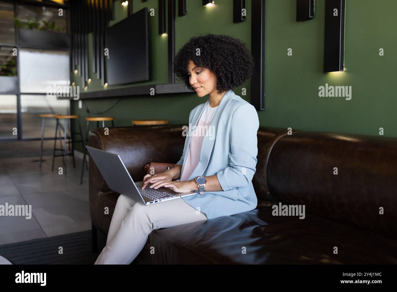 Travailler sur ordinateur portable, femme d'affaires assise sur un canapé dans un espace de bureau moderne Banque D'Images