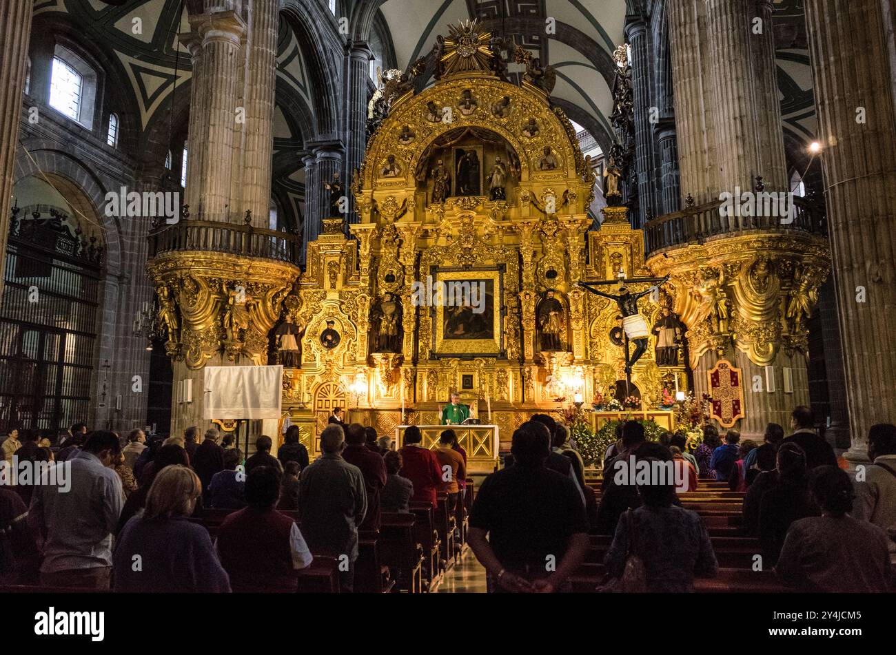 Autel del Perdón Cathédrale métropolitaine de Mexico // MEXICO CITY, Mexique — L'autel del Perdón (autel du pardon) présente une architecture baroque churrigueresque au sein de la Cathédrale métropolitaine de Mexico lors d'un service religieux. Conçu par l'architecte espagnol Jerónimo de Balbás et achevé en 1735, le retablo doré de 12 mètres (39 pieds) de haut présente des colonnes estípite et une peinture centrale de la Vierge du pardon. Historiquement, l'autel a servi de site pour l'absolution finale des criminels condamnés et des masses pénitentielles. Gravement endommagé dans un incendie de 1967, l'autel subit un extase Banque D'Images