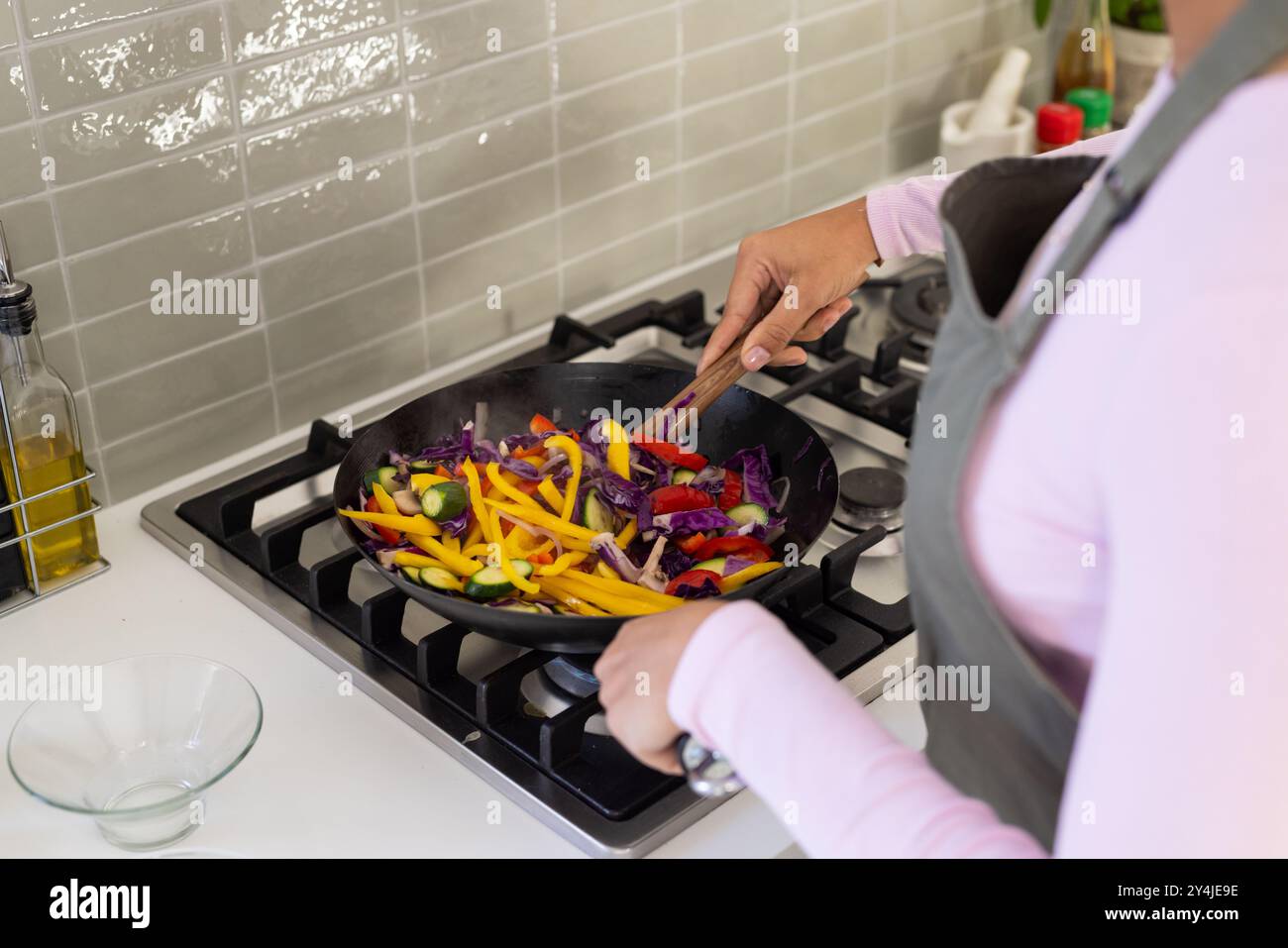 Cuisson de légumes colorés dans un wok, personne préparant un repas sain à la maison Banque D'Images