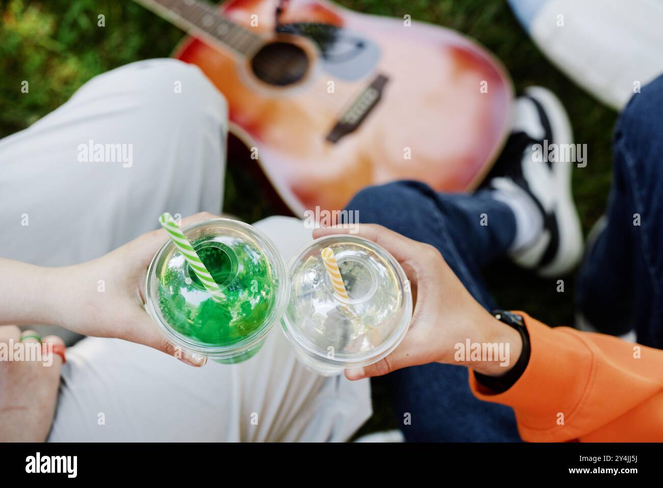 Gros plan sur les mains d'adolescents tenant des gobelets en plastique avec des boissons rafraîchissantes tout en serrant des verres et en profitant d'un pique-nique dans le parc le jour ensoleillé d'été, copiez l'espace Banque D'Images