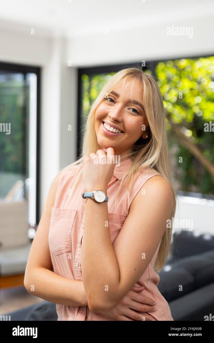 Femme souriante posant à l'intérieur, portant montre-bracelet et chemise sans manches décontractée Banque D'Images