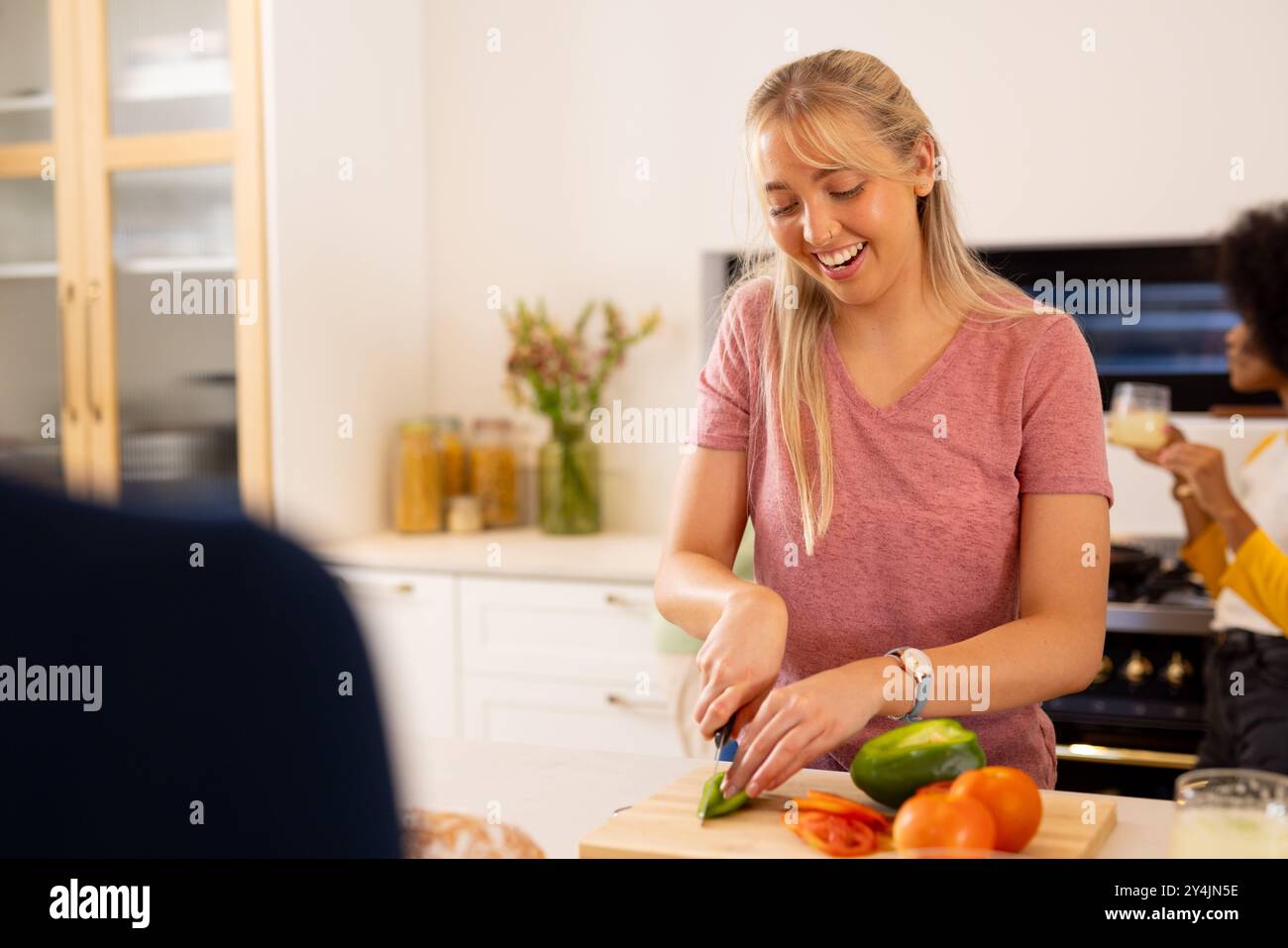 Hacher des légumes, jeune femme souriante et préparer le repas en cuisine avec des amis divers Banque D'Images