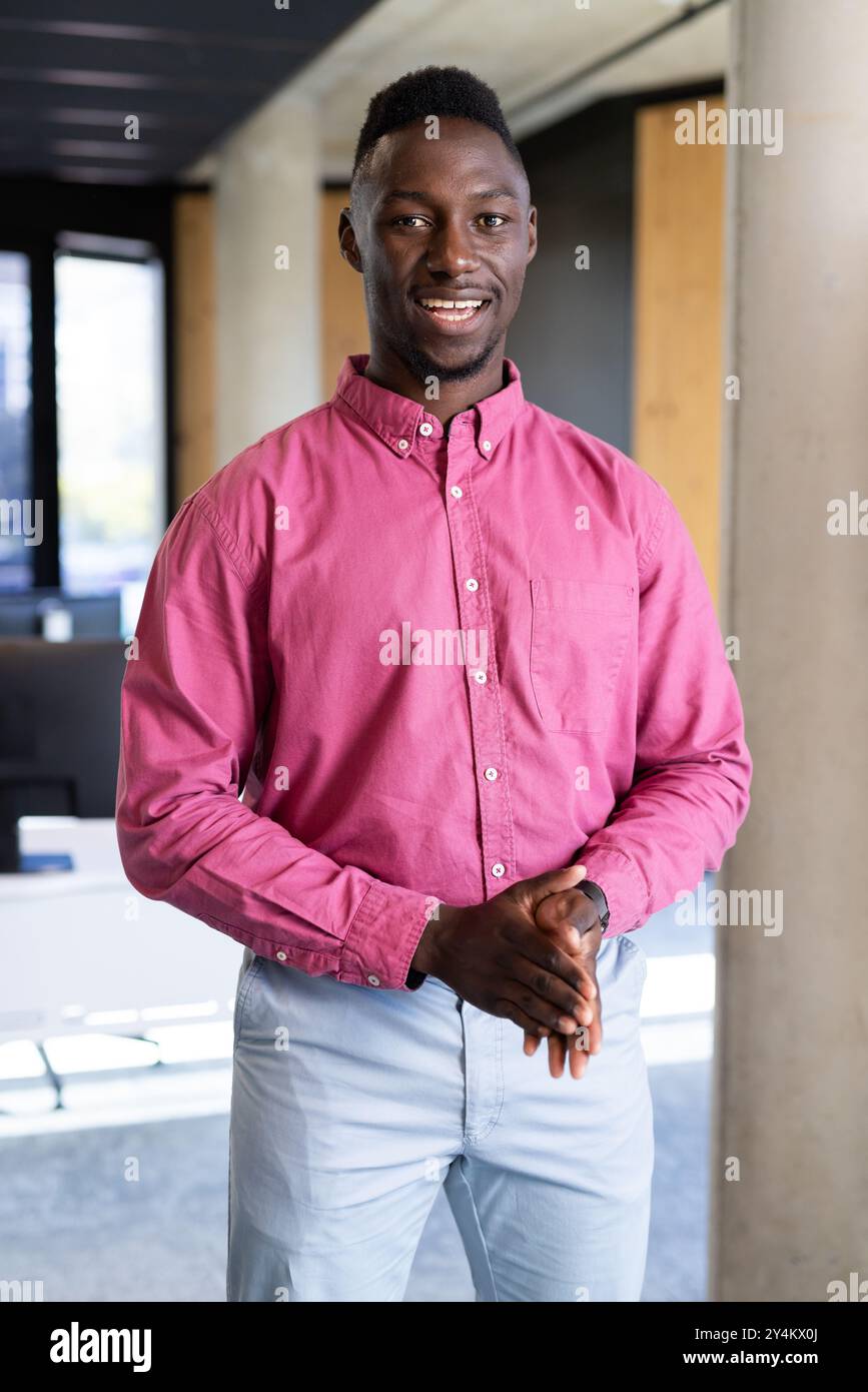 Homme d'affaires souriant au bureau portant une chemise rose et un pantalon bleu clair Banque D'Images