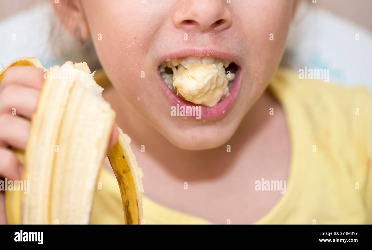 Petit enfant mangeant une banane, gros plan en studio Banque D'Images