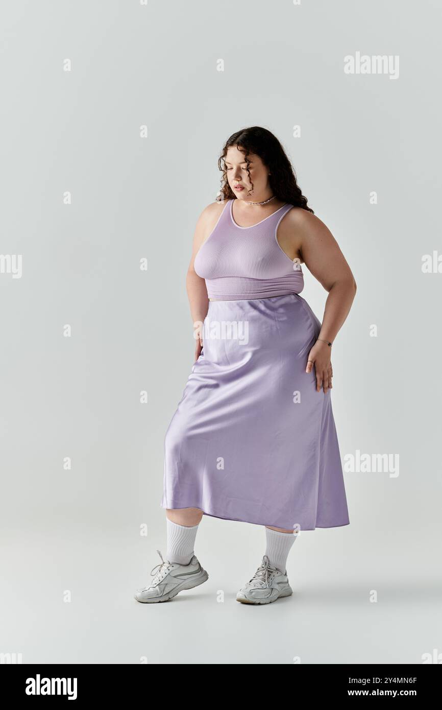 L'élégante femme de grande taille se tient debout dans une robe lavande, rayonnant de confiance et de beauté. Banque D'Images