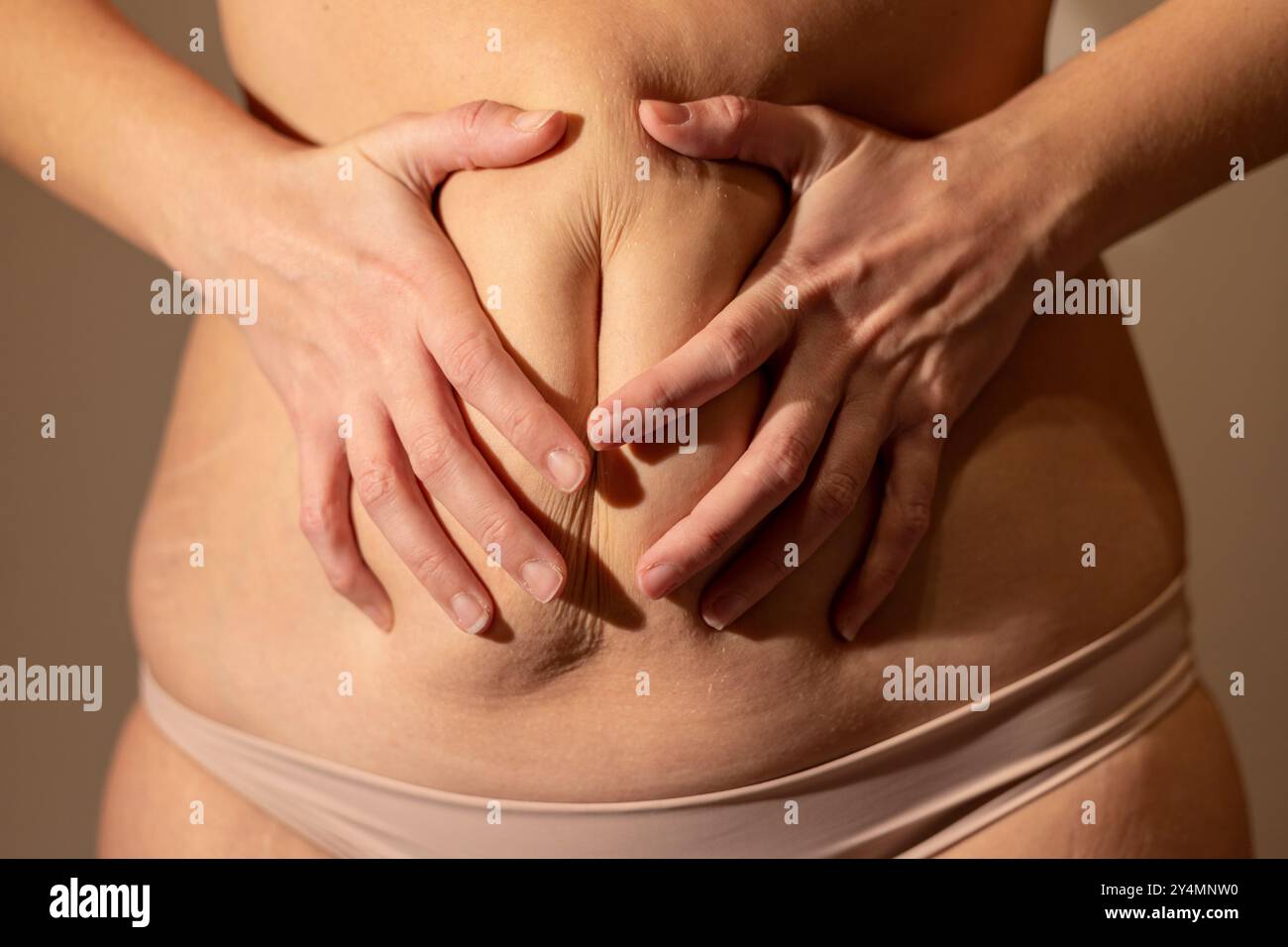 Gros plan d'un corps de femme serrant son ventre. Flou de mise au point Banque D'Images