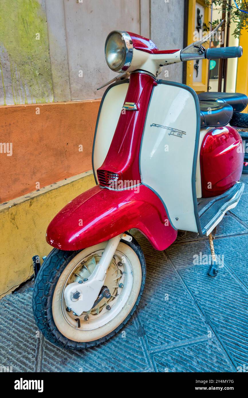 Un scooter Lambretta 150 LI magnifiquement restauré avec une palette de couleurs rouge et blanc, garé contre un mur coloré. Banque D'Images