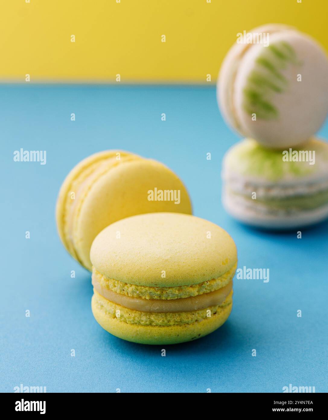 Macarons doux et colorés sur bleu avec fond jaune Banque D'Images