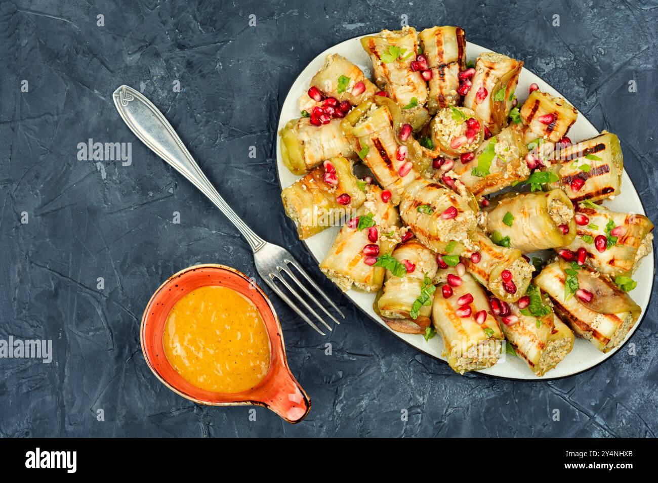 Rouleaux d'aubergines frites avec noix, garniture à l'ail et décorés de grenade. Badrijani Banque D'Images