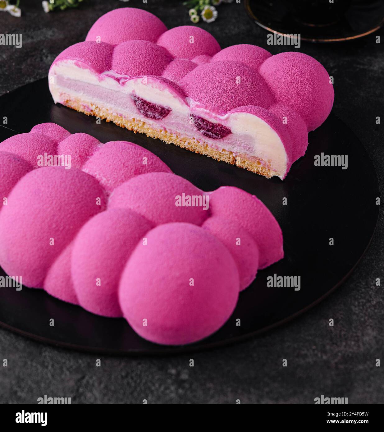 Gâteau mousse de framboise contemporain sur assiette noire Banque D'Images