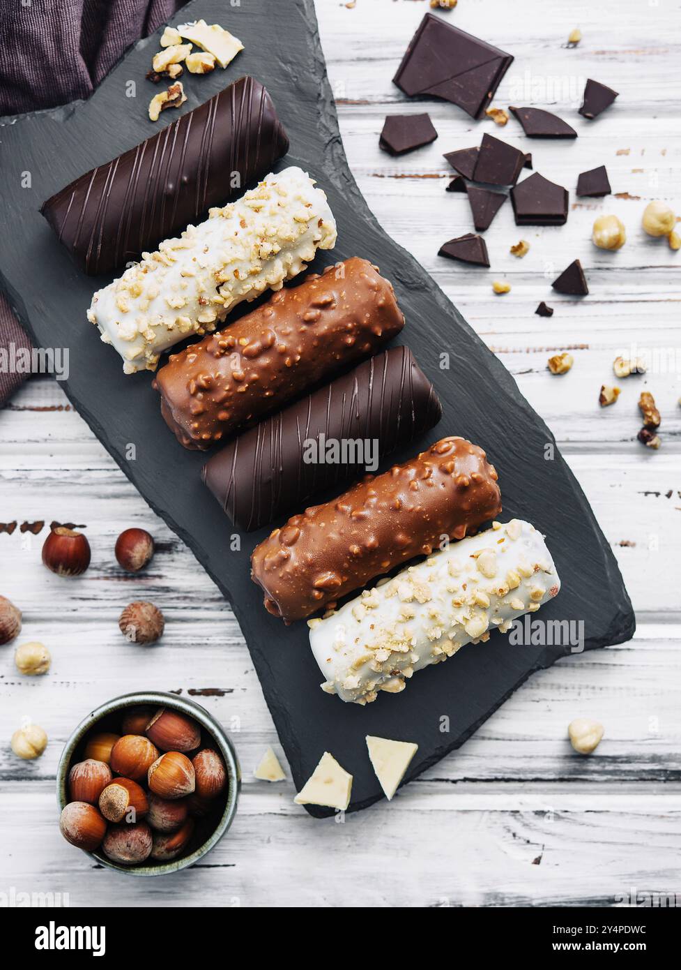 Dessert français éclairs ou profiteroles avec différents glaçons au chocolat sur une assiette en pierre noire Banque D'Images