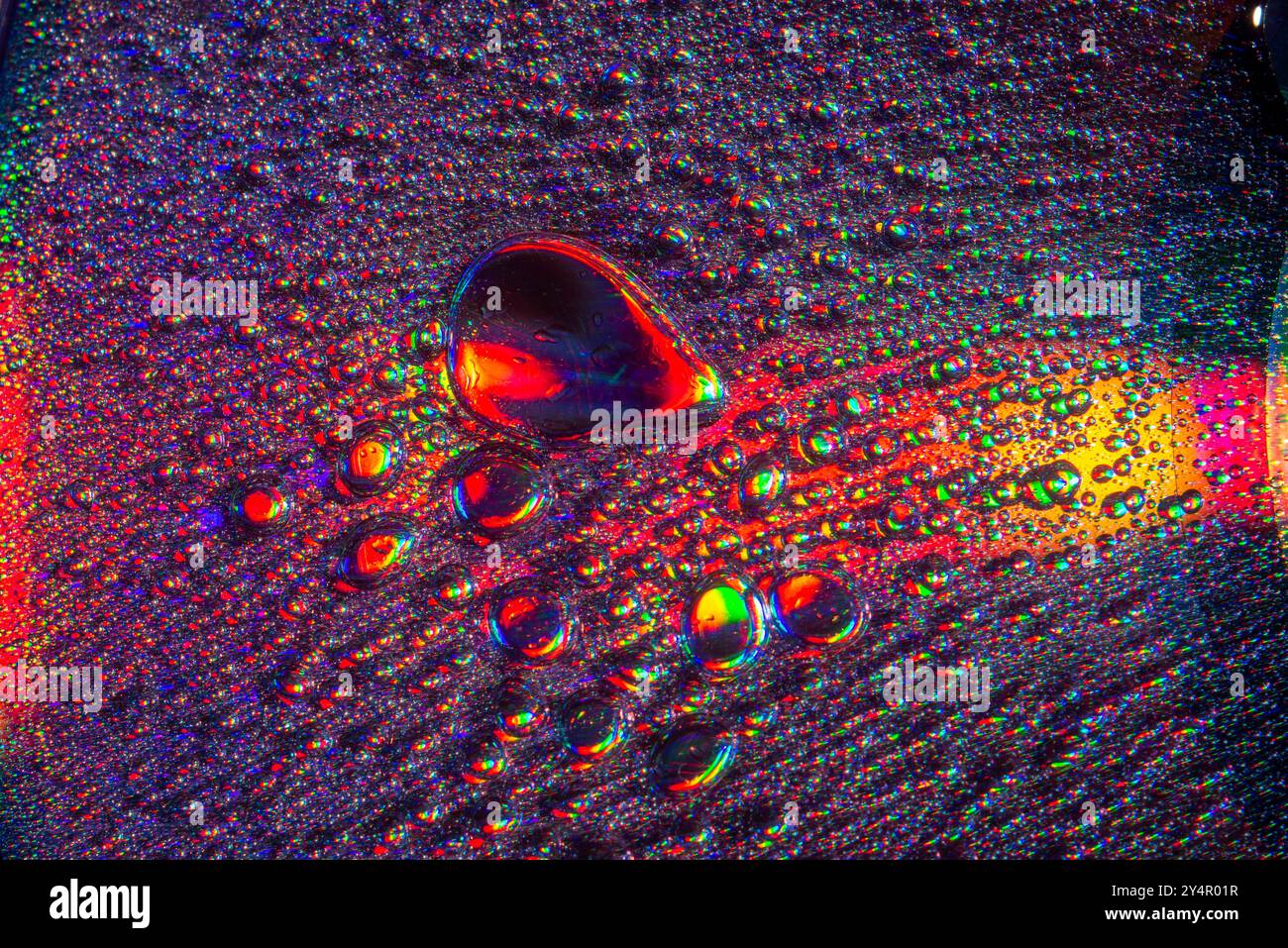 Une photo macro montrant des motifs et des couleurs de gouttes d'huile flottant sur l'eau Banque D'Images